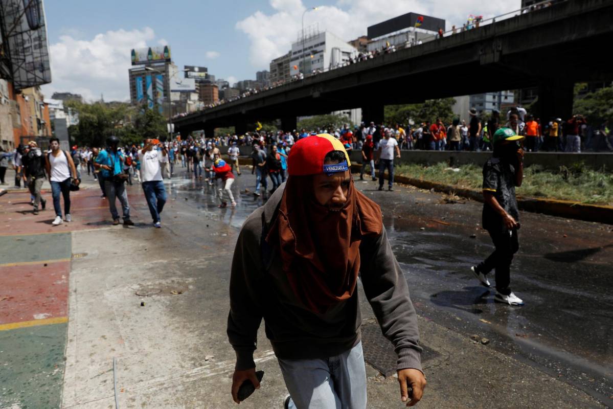 Al mismo tiempo, otro grupo de manifestantes se dispersaron al ver las lacrimógenas, una decena más retrocedía y otros corrían hacia las vías transversales. FOTO REUTERS