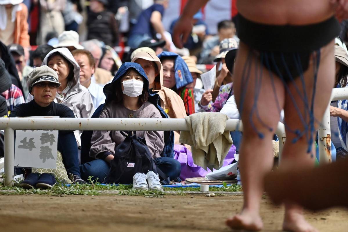 Los espectadores observan cómo los luchadores de sumo participan en un “honozumo”, una exhibición ceremonial de sumo, en los terrenos del Santuario Yasukuni en Tokio. Foto: CHARLY TRIBALLEAU / AFP