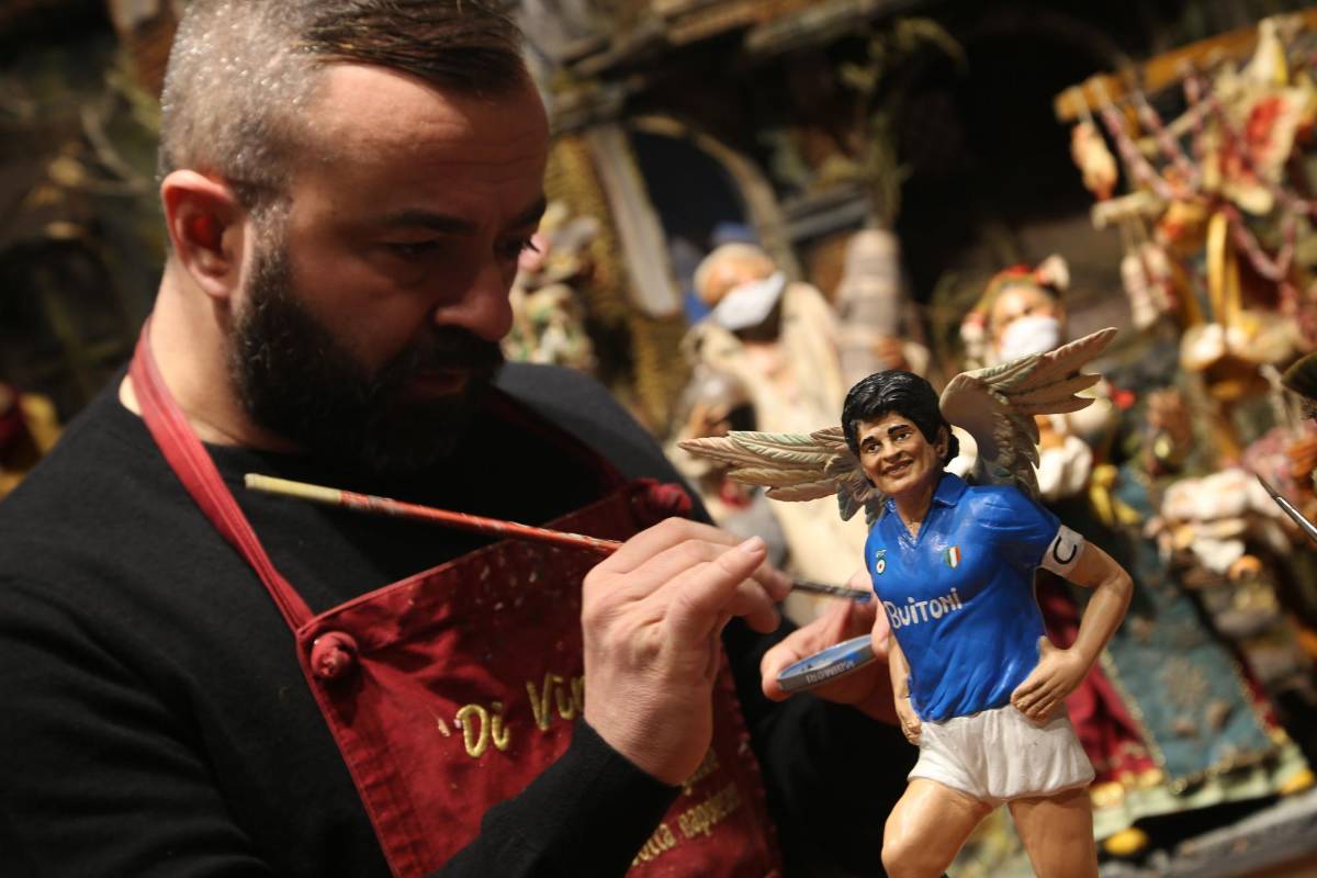 En esa misma ciudad, un artista pinta una pequeña escultura de Maradona con alas y vistiendo el uniforme de Nápoles. FOTO AFP