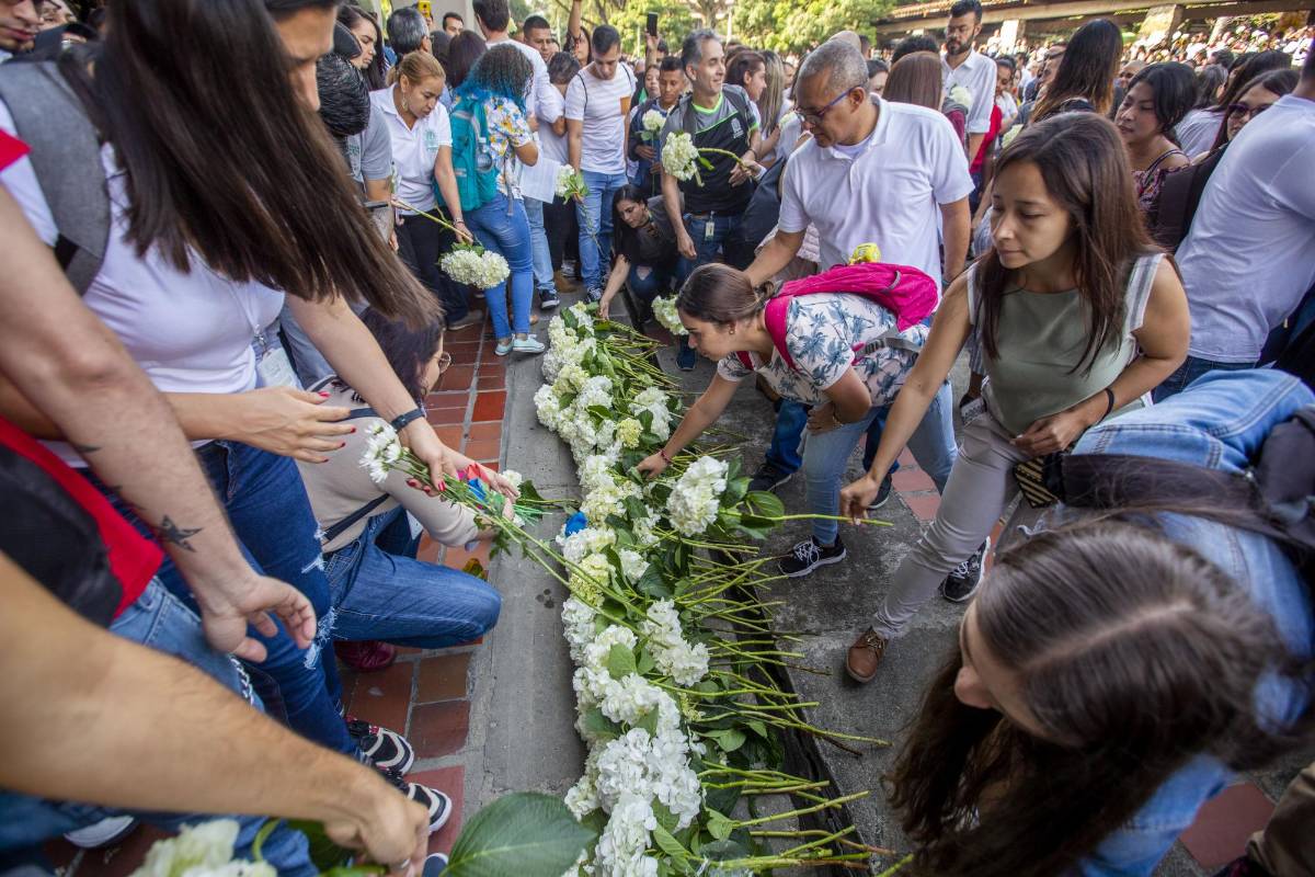 Flores y pancartas fueron llevados por la comunidad universitaria en un acto simbólico para rechazar los actos violentos.
