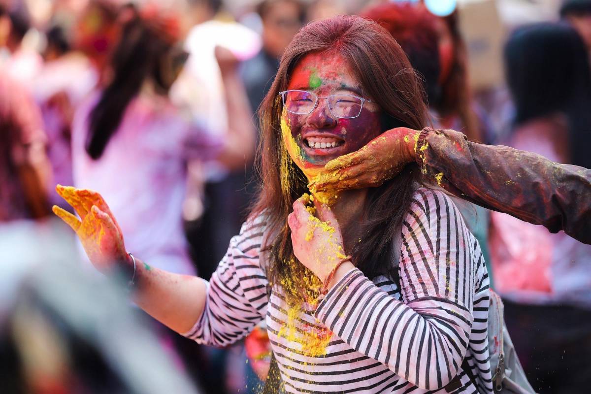 Los jóvenes sonríe embadurnados de colores mientras una multitud celebra, este miércoles, el festival Holi . Foto: EFE/ Divyakant Solanki