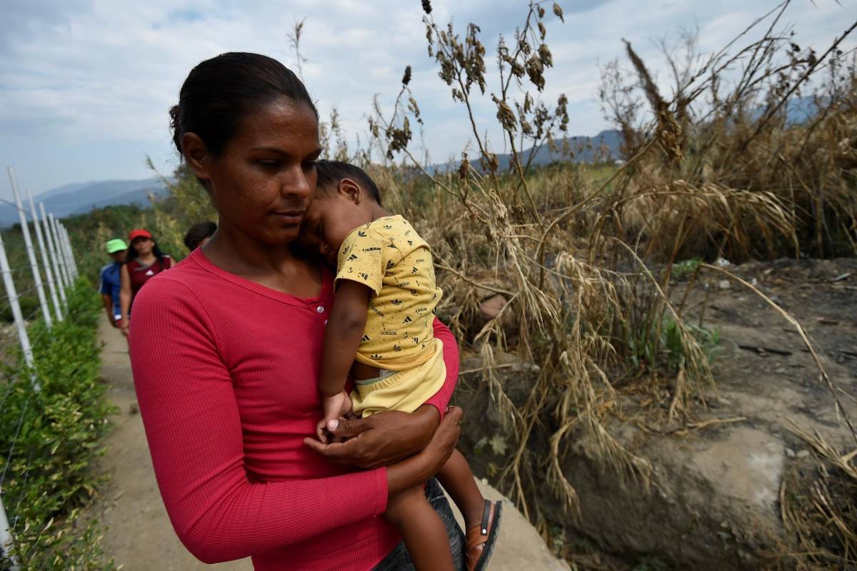 Una mujer y su hijo cruzan un sendero ilegal a través del río Táchira desde San Antonio, Venezuela hasta Cúcuta. FOTO AFP