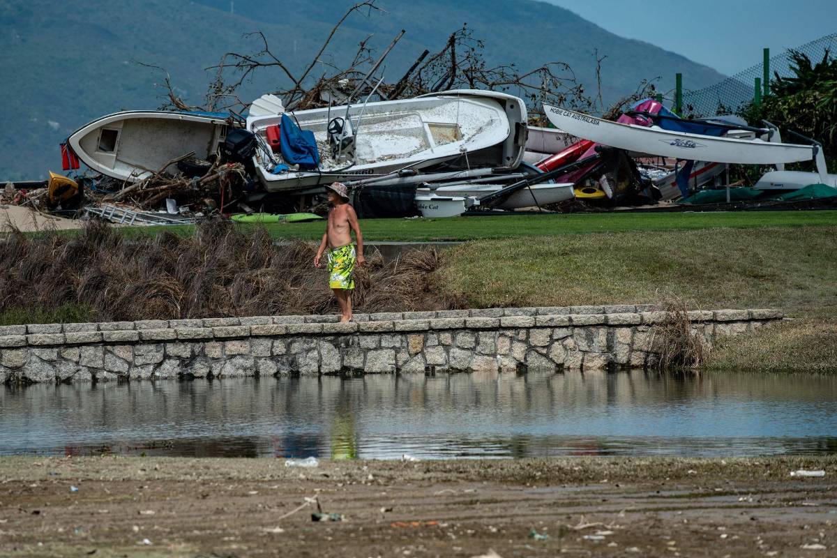 Un hombre cruza un puente de piedra sobre un obstáculo de agua en un campo de golf mientras busca su bote en la aldea costera de Shek O, Hong Kong. Foto: AFP