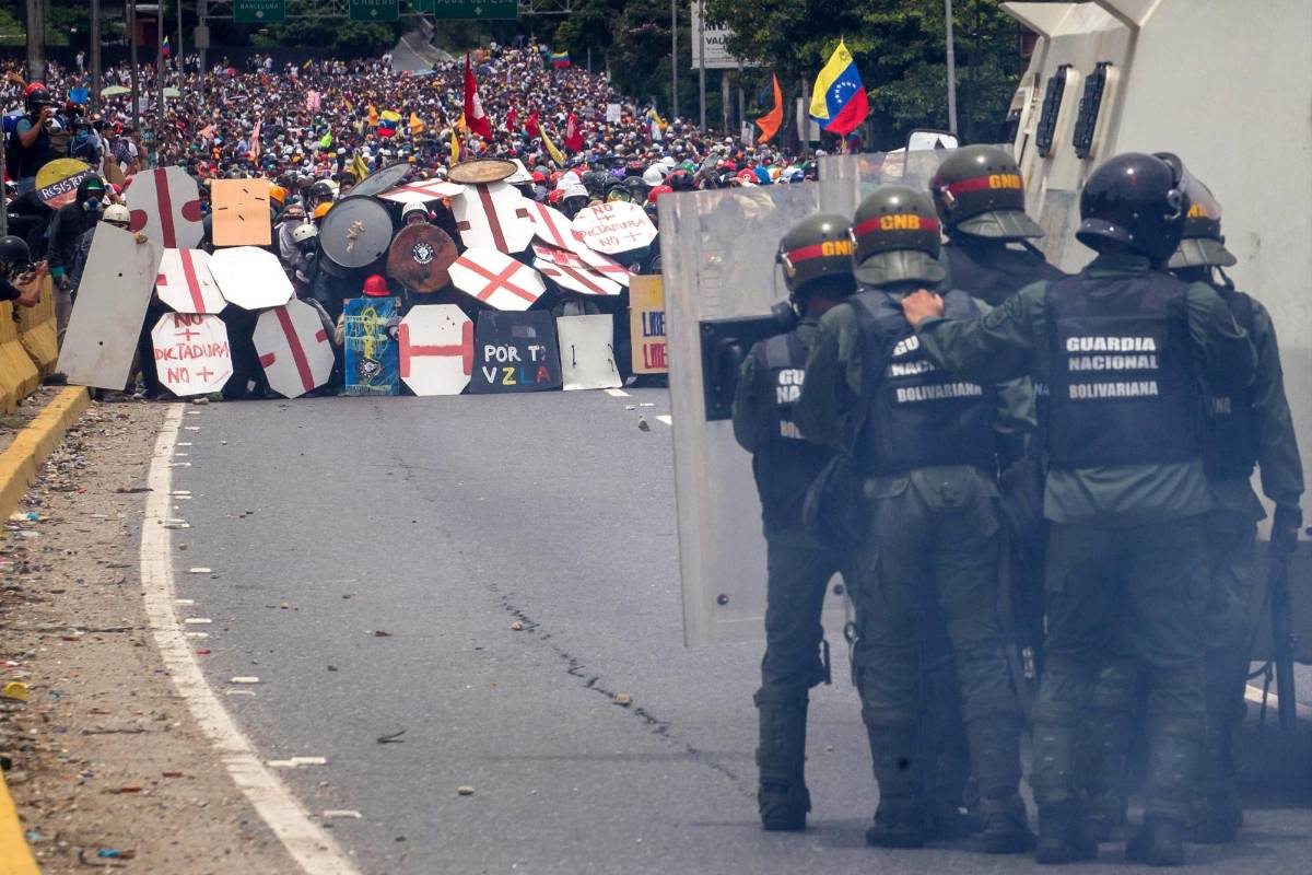 Algunos miembros de la oposición defiende con escudos artesanales a manifestantes de agentes de la Guardia Nacional Bolivariana. EFE