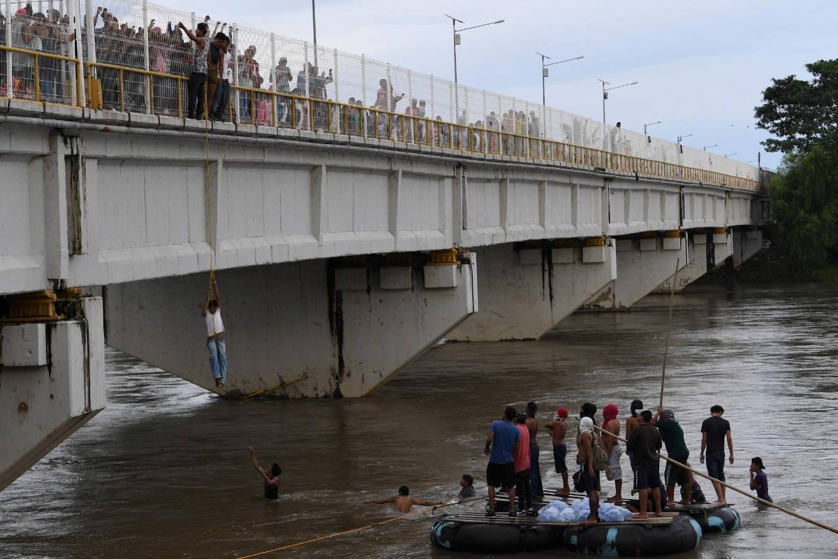 Miles de migrantes hondureños, que salieron en caravana de su país con destino a Estados Unidos, viven una tensa espera en el puente fronterizo entre México y Guatemala. AFP