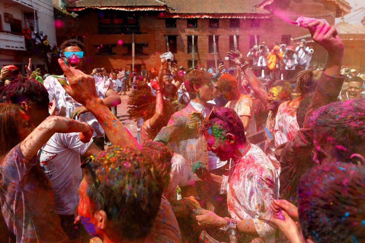 Los jóvenes sonríe embadurnados de colores mientras una multitud celebra, este miércoles, el festival Holi . Foto: EFE / Divyakant Solanki 
