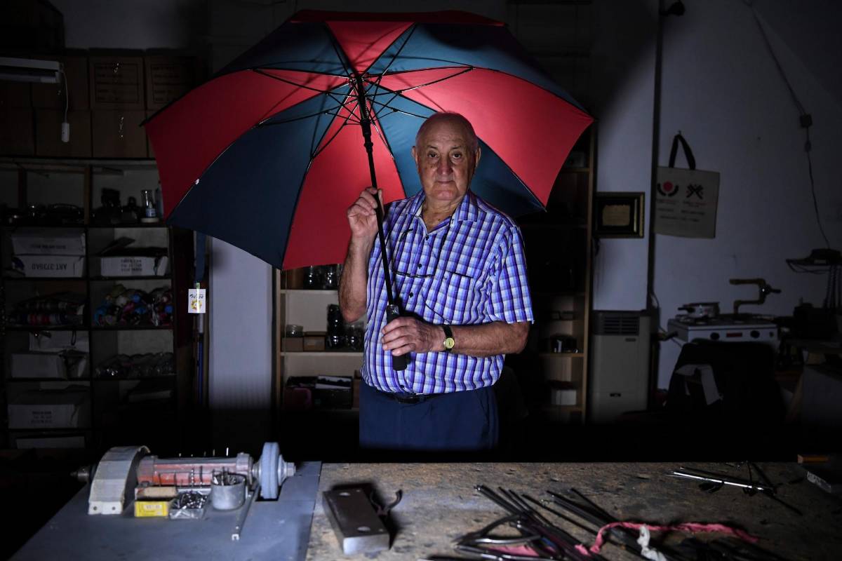 Elias Fernández, arregla paraguas en su taller en Buenos Aires, Argentina. FOTO: EITAN ABRAMOVICH; AFP.