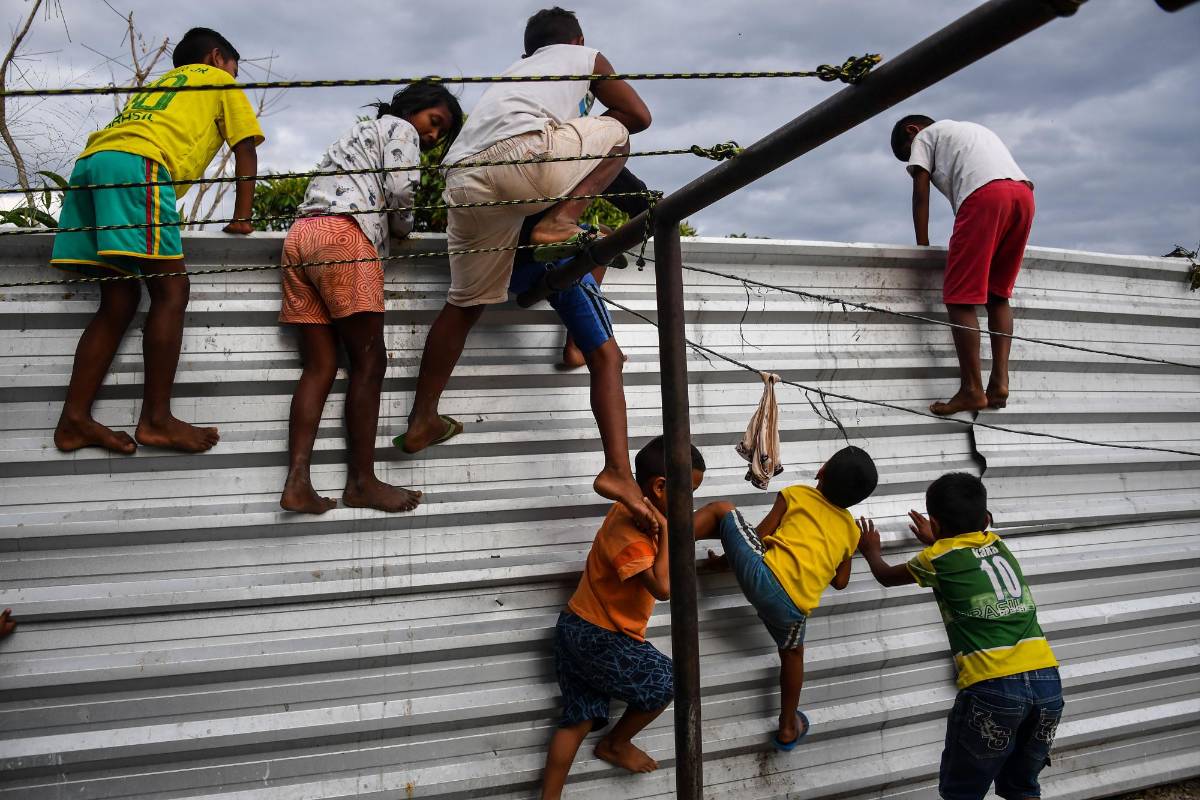 Niños indígenas venezolanos de la tribu Warao escalan una cerca en el refugio de Janokoida donde se han refugiado en Pacaraima, estado de Roraima, Brasil, en la frontera con Venezuela. FOTO AFP