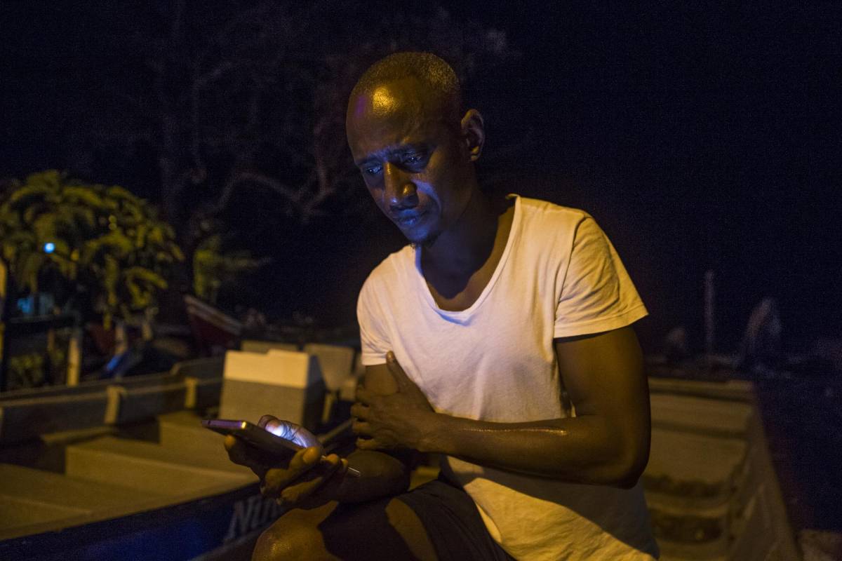 Ibrahim Muctar Jalloh de Sierra Leona lleva varios meses en Capurganá. Su única forma de comunicarse con la familia es a través de redes sociales en su celular. Pasó varios meses detenido en un campo de refugiados en Panamá donde según él tuvo que cortarse el brazo izquierdo para que lo dejaran salir. Foto: Esteban Vanegas