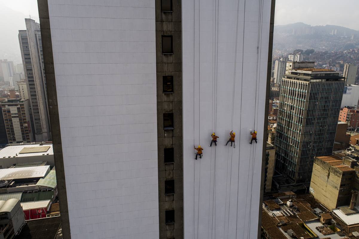 Los obreros desafían la gravedad para darle una mano de pintura al edificio. Esteban Vanegas