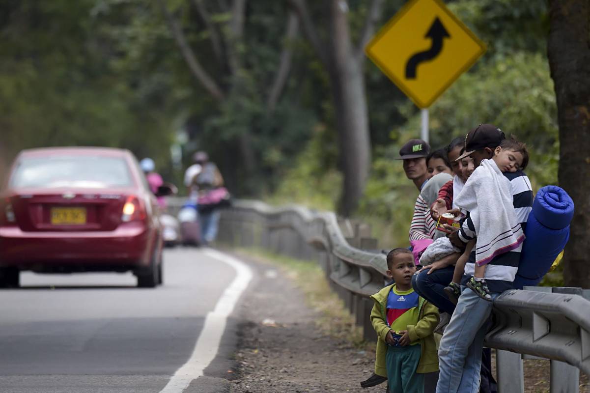 Los migrantes venezolanos descansan mientras caminan por la carretera de Cúcuta a Pamplona, en el departamento de Norte de Santander, Colombia. FOTO AFP