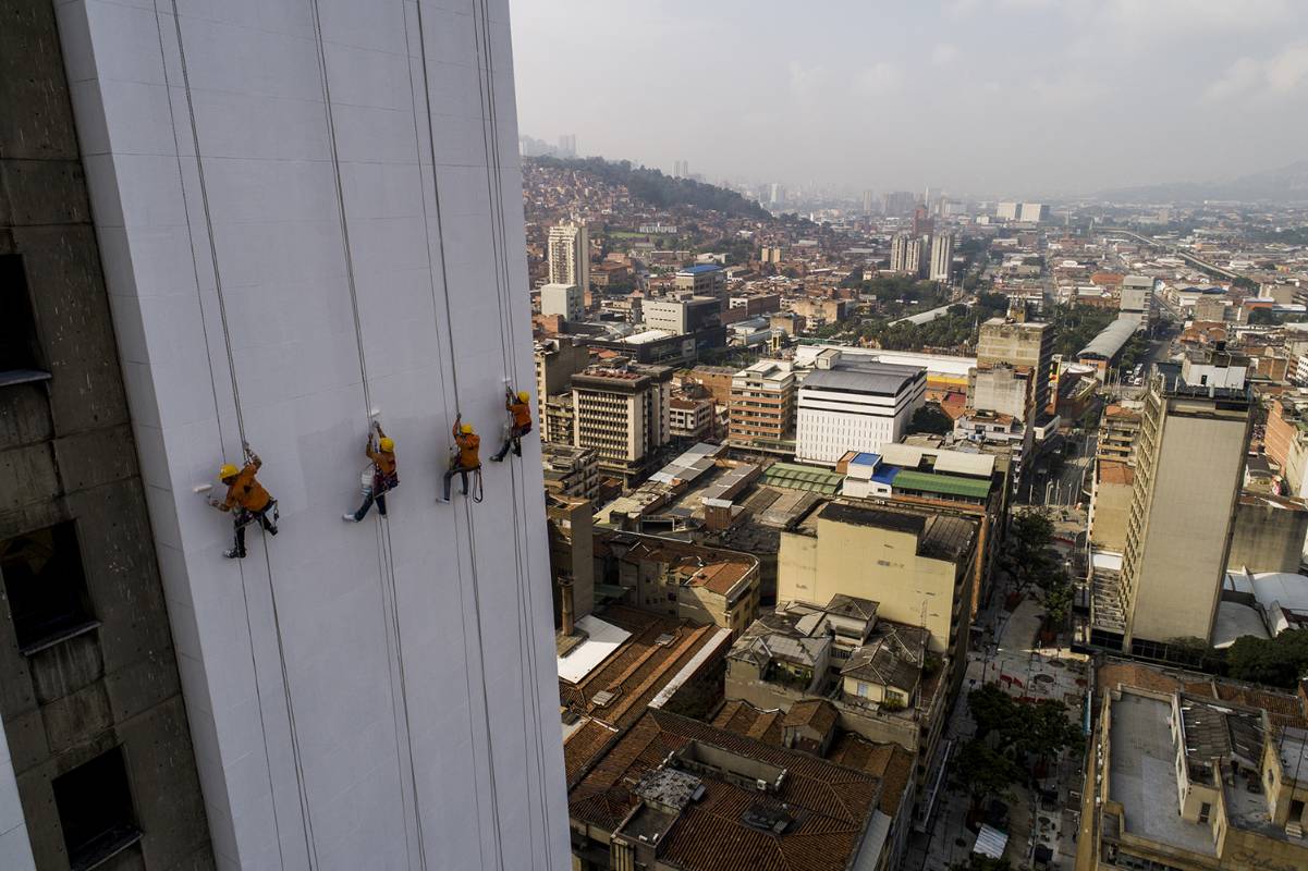 Los obreros desafían la gravedad para darle una mano de pintura al edificio. Esteban Vanegas