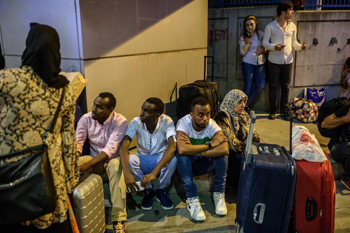 Grupos de pasajeros esperan sentados recibir alguna noticia sobre el paradero de sus maletas. FOTO AFP 