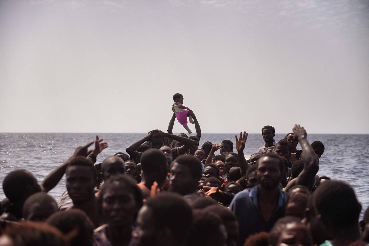 Migrantes libios esperan a ser rescatados en medio del mar mediterraneo tras huir d ela guerra en su país. FOTO ARIS MESSINIS, AFP