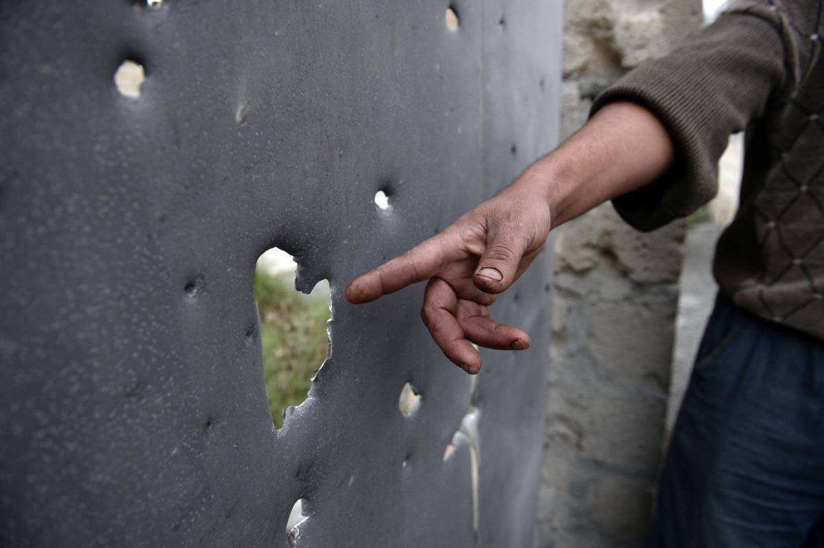 Un hombre señala una puerta que se dice que fue dañada en los recientes bombardeos durante los enfrentamientos. Foto: AFP