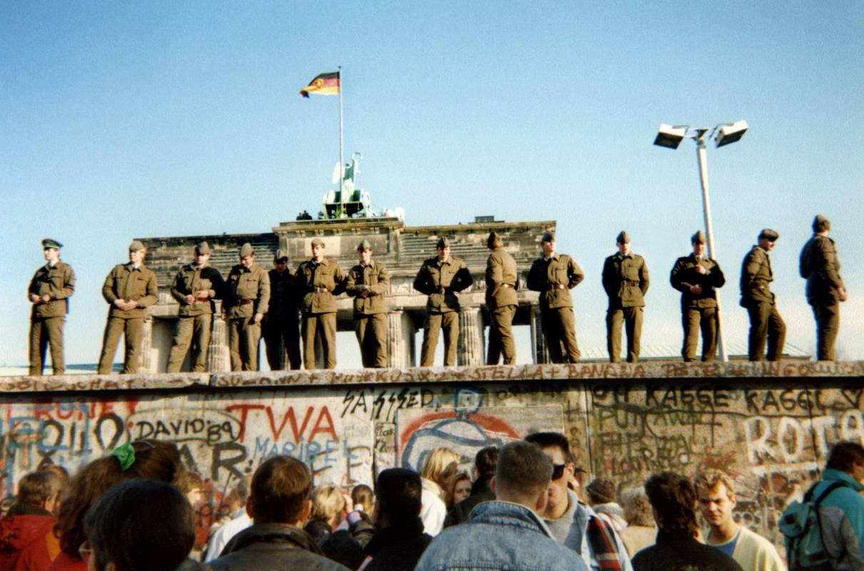 Guardias fronterizos de Alemania Oriental se paran en una sección del muro de Berlín con la Puerta de Brandeburgo al fondo. Foto de archivo tomada el 11 de noviembre de 1989. FOTO AFP 