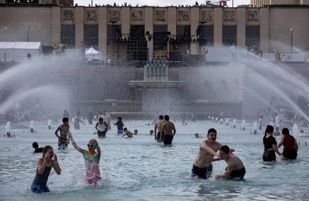 Varias personas se refrescan con el agua de la fuente de la Plaza del Trocadero, frente a la Torre Eiffel, durante la ola de calor que recorre París. Las temperaturas llegarán a los 40 grados centígrados esta semana. Foto: EFE