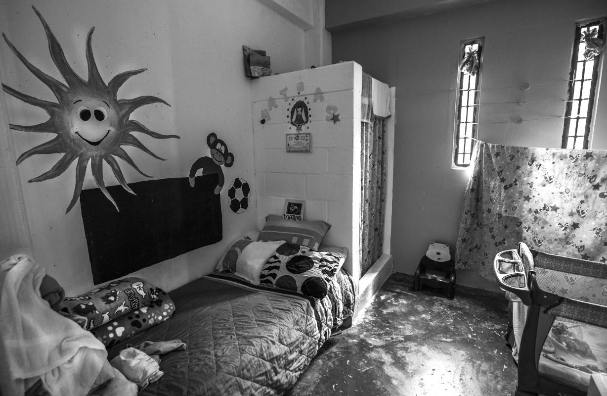 Tras las rejas, la vida de madres e hijos continua entre juegos, ropa, dibujos y un espacio aproximadamente de siete metros de largo por cinco de ancho que los separa de la sociedad. Para las madres es un encierro mientras pagan su condena, para los niños un espacio donde las risas y los juegos es el acto más liberador. Foto: Manuel Saldarriaga Quintero.
