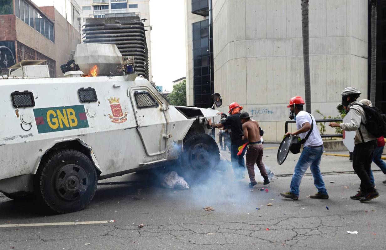 Tanqueta de la Guardia Nacional Bolivariana pasa por encima de un manifestante de la oposición. AFP