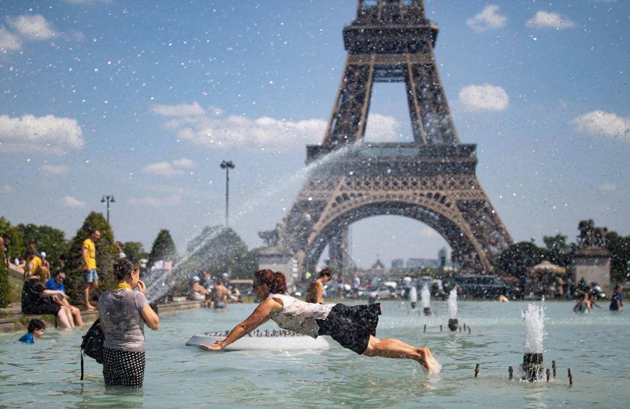 Una mujer se refresca con el agua de la fuente de la Plaza del Trocadero, frente a la Torre Eiffel, durante la ola de calor que recorre París. Las temperaturas llegarán a los 40 grados centígrados esta semana. Foto: EFE