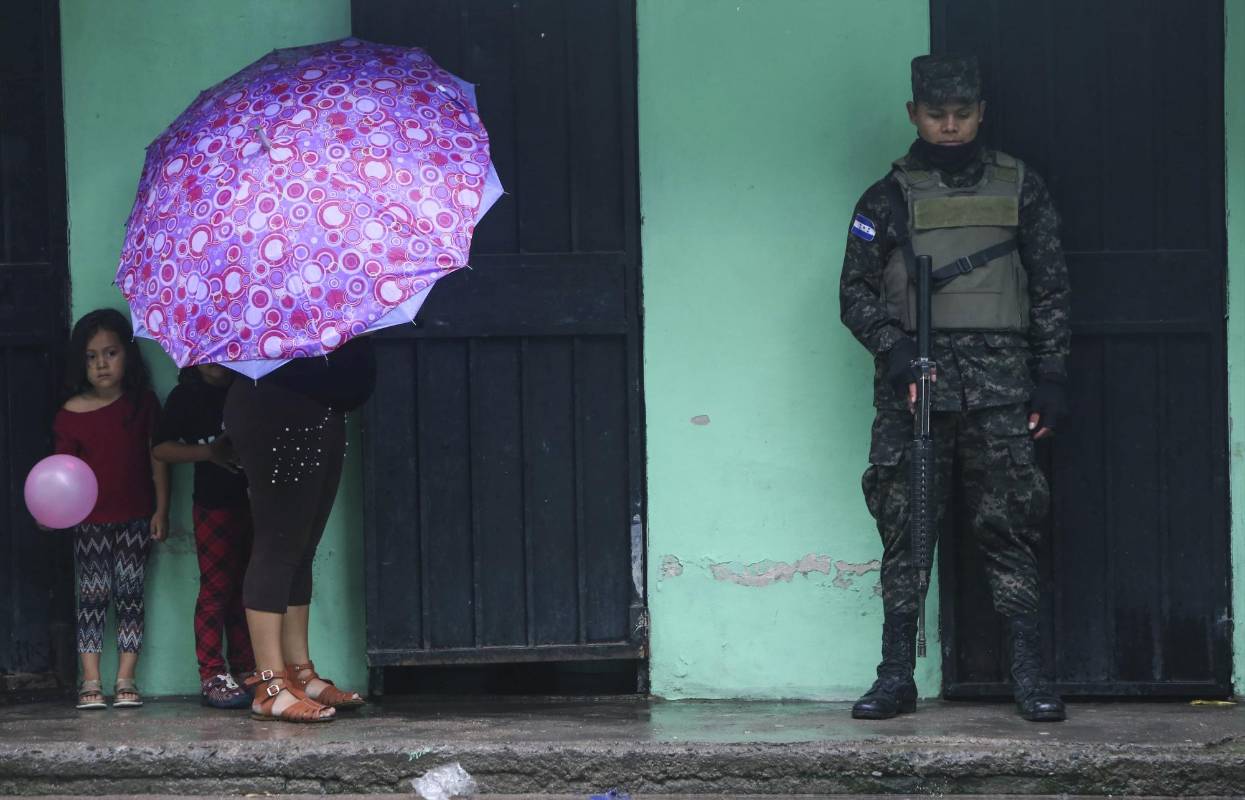 Una mujer y sus hijos permanecen junto a un soldado en la escuela Juan Guifarro López, utilizado como refugio, durante las fuertes lluvias en Tegucigalpa. Foto AFP