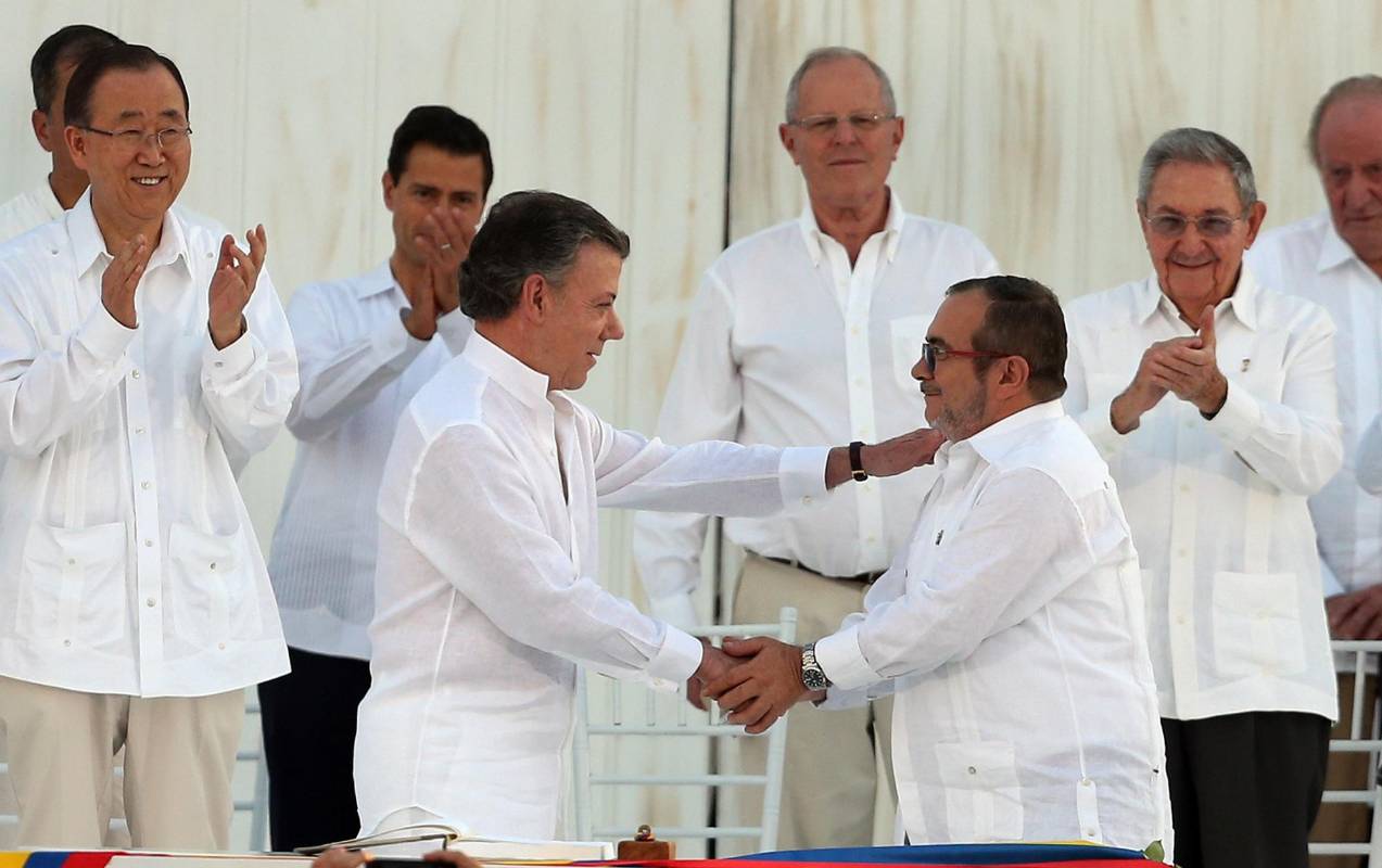 Luego de firmar los acuerdos, el presidente Juan Manuel Santos y el comandante de las Farc, Rodrigo Londoño, estrecharon sus manos en medio de un gran aplauso. FOTO AFP