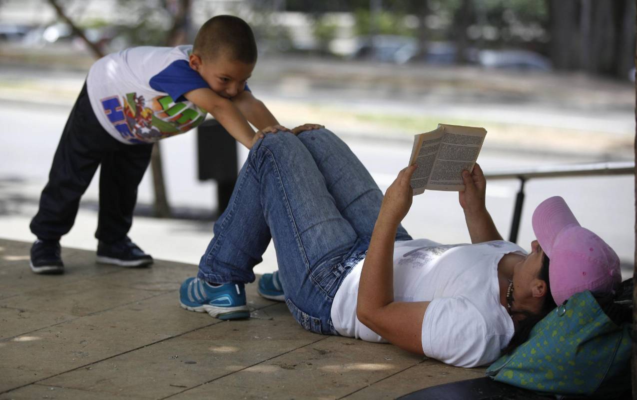 En medio de la agitada rutina de la ciudad, lectores espontáneos aprovechan un momento de calma para leer un buen libro. Foto: Manuel Saldarriaga.