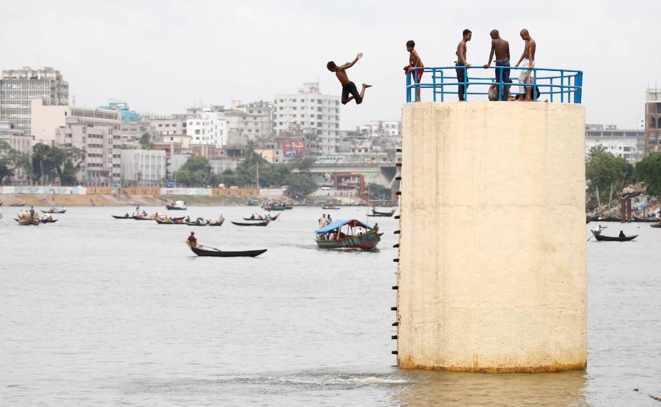 Jóvenes bangladesíes se lanzan al agua del río Buriganga para combatir las altas temperaturas en Dacca, Bangladesh. Foto: EFE