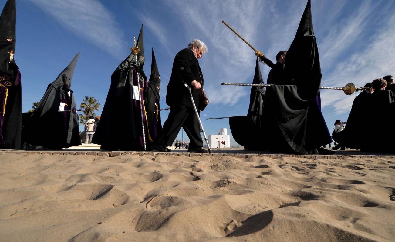 Hermanos de la comunidad Cristo Salvador caminan en la arena de una de las playas de Valencia (España) durante una de las procesiones de Semana Santa en España. FOTO AFP 