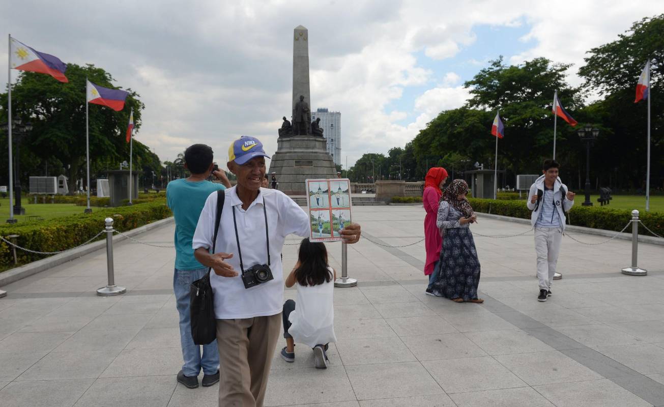 Joel Estrella, fotógrafo de parques, ofrece sus servicios de fotografía a turistas en un parque en Manila. FOTO: TED ALJIBE; AFP.