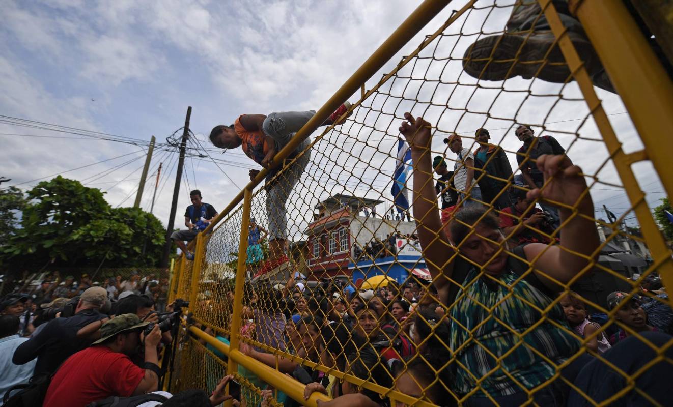 Miles de migrantes hondureños, que salieron en caravana de su país con destino a Estados Unidos, viven una tensa espera en el puente fronterizo entre México y Guatemala. AFP