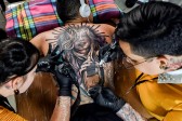 A dos manos realizan un gigantesco tatuaje en la espalda. Foto: AFP