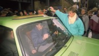 Una berlinesa occidental (der.) da la bienvenida a un berlinés oriental mientras vierte champán en su automóvil en Wollangstrasse, donde se abrió un punto de cruce hacia el oeste. Foto de archivo tomada el 13 de noviembre de 1989. FOTO AFP