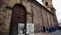 Un policía y un hombre de civil se resguardan al lado de una de las puertas sobre la calle 11 de la catedral Primada de Bogotá. FOTO Mauricio Alvarado- Colprensa