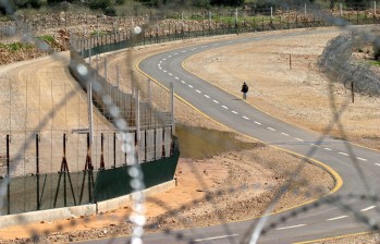 Una palestina camina junto a una valla de seguridad construida para separar a Israel de Cisjordania. FOTO REUTERS