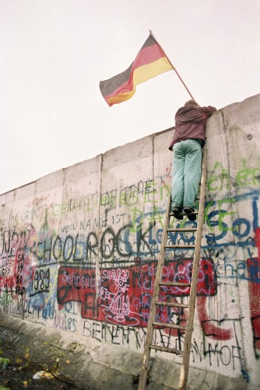 Un berlinés occidental se prepara para entregar una bandera a policías de Vopo de Alemania Oriental, a través de una porción del muro de Berlín. Foto de archivo tomada el 11 de noviembre de 1989. FOTO AFP