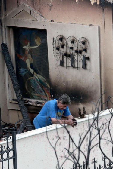 Un hombre observa desde su balcón los daños que dejó el incendio en Mati. FOTO EFE