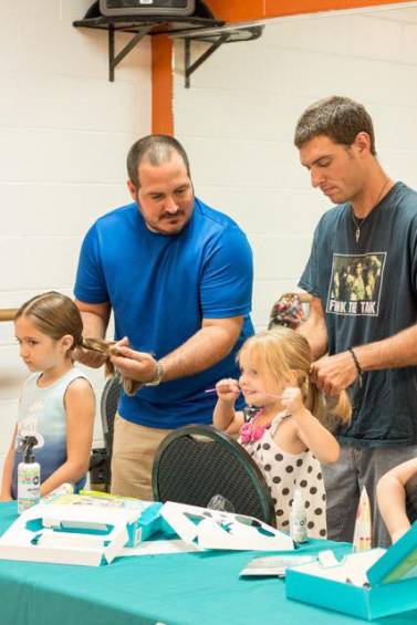 Philippe y su hija Emma (izquierda) le explican a un papá como hacer una trenza . FOTO Facebook