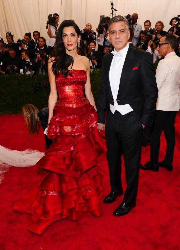 George Clooney y su esposa Amal combinaron sus atuendos con toques de rojo, el diseño de Amal es de John Galliano para Margiela. FOTO AP