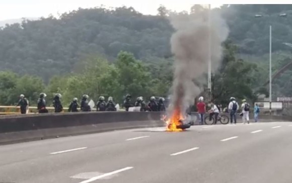 Moto en llamas sobre el puente de Barranquilla (carrera 67) durante los disturbios en la U. de A. FOTO CORTESÍA