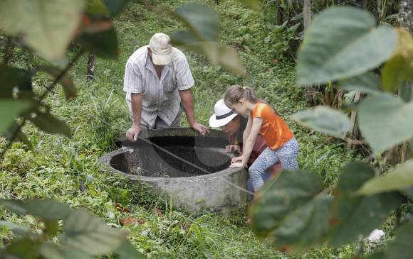 Edgardo, Luz Maryory y su hija Isabella observan el agua que comienza a brotar del pozo, en su finca de la vereda La Quiebra en Rionegro, Oriente de Antioquia. FOTO Manuel Saldarriaga