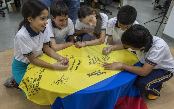 Los niños también le escriben, en la bandera de Colombia, sus buenos deseos a Mariana Pajón. FOTO Róbinson Sáenz
