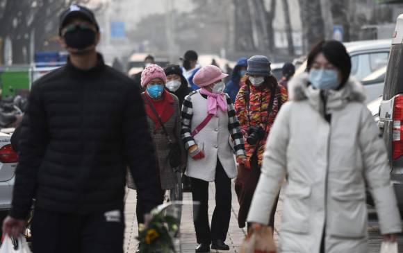 Personas usan máscaras protectoras mientras caminan cerca a un mercado en Pekín, este 9 de febrero. FOTO AFP
