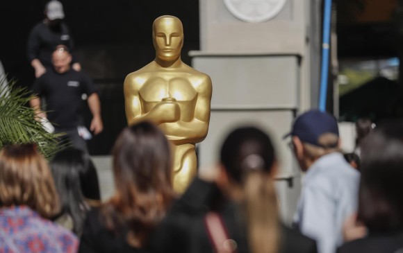 Personas se toman fotos junto a una estatua de un Oscar mientras continúan los preparativos de la alfombra roja para la ceremonia anual de los Premios Oscar. FOTO EFE