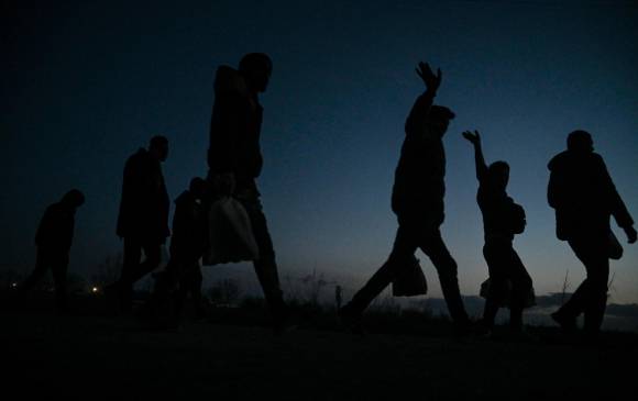 Refugiados y migrantes saludan mientras caminan hacia un campamento en el lado turco de la frontera entre Turquía y Grecia cerca de la puerta de cruce de Pazarkule en la provincia de Edirne el 7 de marzo de 2020. FOTO: AFP