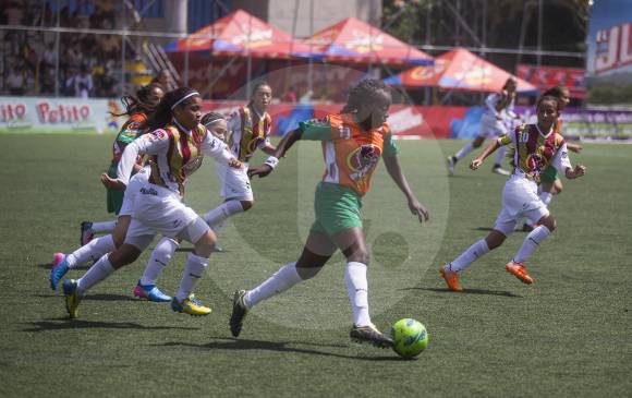 Una de las integrantes del equipo Sibundoy de Putumayo (uniforme naranja) transporta el balón en el partido del debut en el Ponyfútbol. FOTO esteban vanegas
