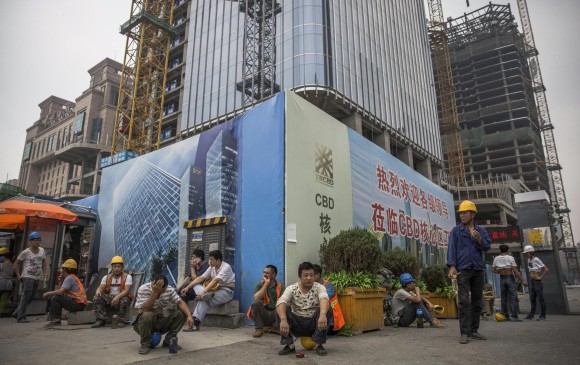 Obreros migrantes, ayer a la hora del almuerzo en las obras de un proyecto en el distrito financiero de Pekín (China). FOTO REUTERS