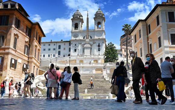 En Roma ya hay transeúntes. Deben portar tapabocas y guardar un metro de distancia, lo que no se cumple en la foto. FOTO AFP