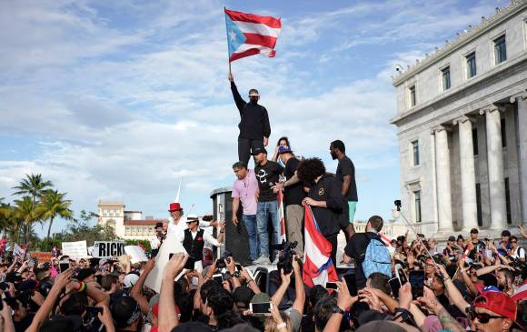 En la imagen se ve a varios músicos, entre ellos Bad Bunny el cantante “Residente” presidiendo las protestas contra el gobernador Ricardo Roselló. En los pantallazos algunos de los chats filtrados en los que el mandatario se burla del peso de un seguidor que saluda con comentarios como “genera un campo de gravedad muy fuerte”. En el pantallazo de la derecha, Roselló llama “Puta” a una funcionaria demócrata. FOTOS AFP y centro de periodismo investigativo