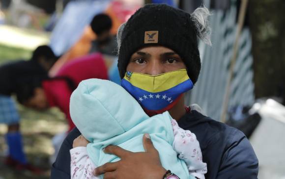 Un ciudadano venezolano sostiene a su hija mientras posa para Efe en un campamento creado hace unos días, en el separador de la Autopista Norte, en Bogotá. FOTO EFE